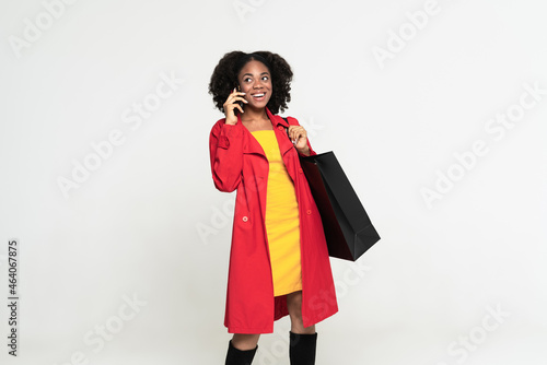 Young black woman talking on cellphone while posing with shopping bag