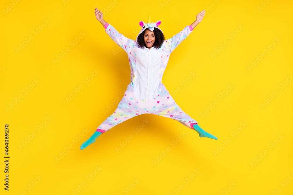 Full length photo of young afro woman happy positive smile jump up nightwear playful isolated over yellow color background
