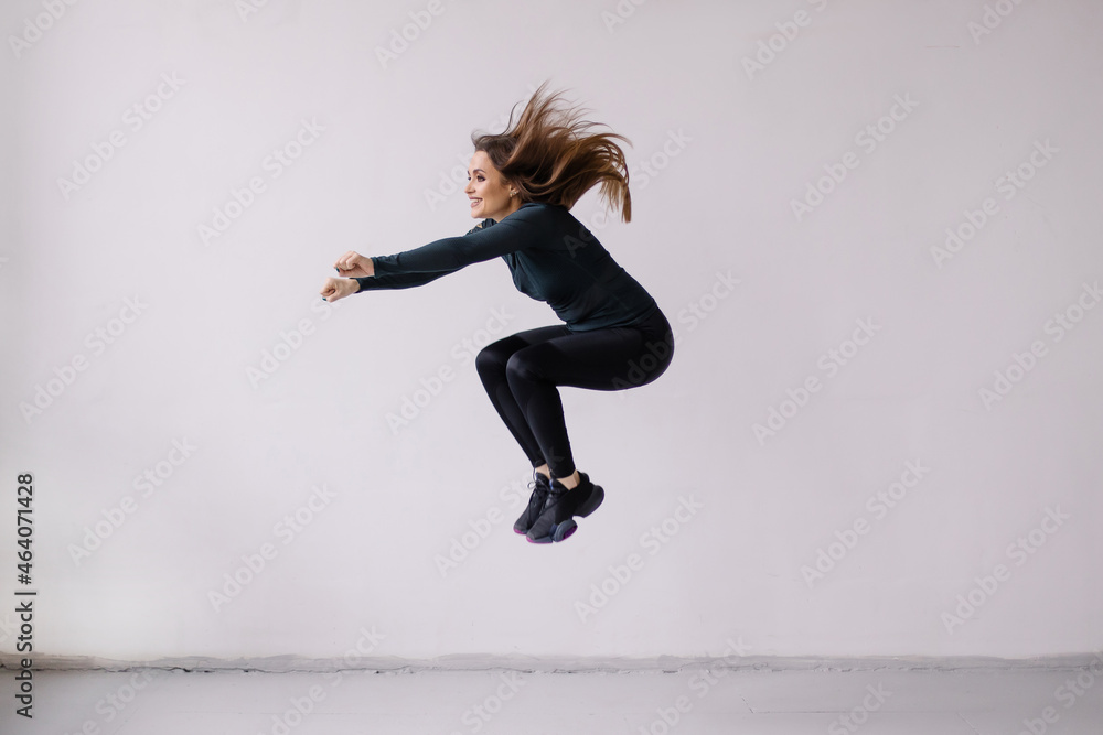 Stylish woman in sportswear is exercising. Jumping exercise in the gym. Black leggings sport. fitness aerobics. Lifestyle movement. Cardio. jump squat. 