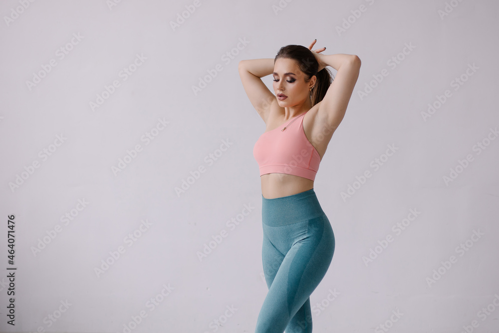 Confident pose of fitness trainer portrait. Fashion woman in sportswear. Strong beautiful sportswoman with make-up. Lifestyle. Sportive curvy sensual girl with a muscular figure. Healthy gym workout Confident pose of fitness trainer portrait. Fashion woman in sportswear. Strong beautiful sportswoman with make-up. Lifestyle. Sportive curvy sensual girl with a muscular figure. Healthy gym workout