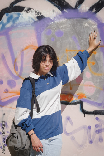 Schoolgirl girl posing against colorful graffiti wall