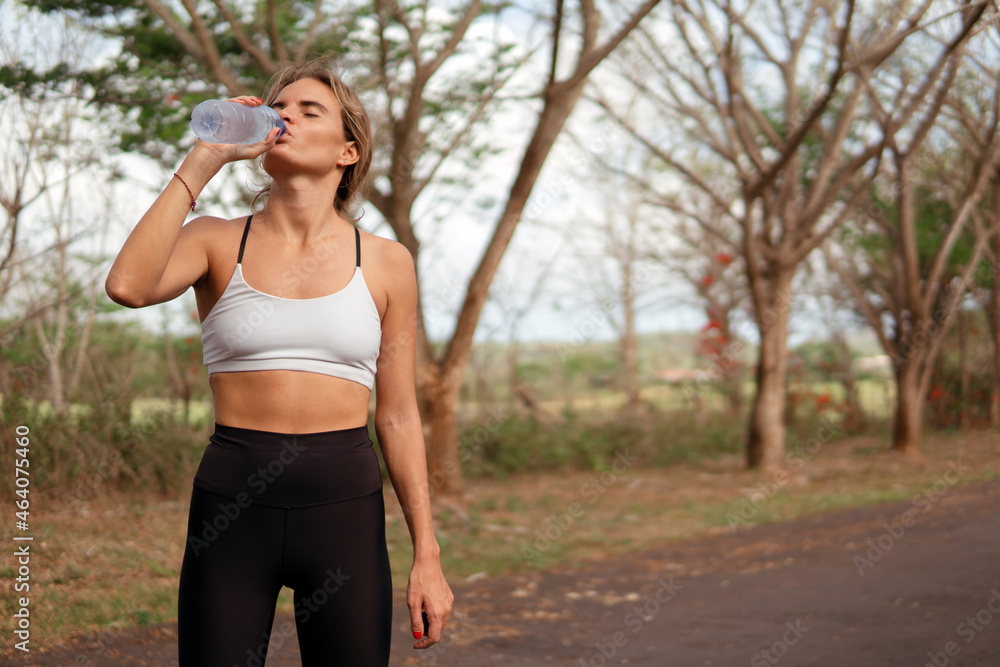 Woman drinking water in the park Woman drinking water in the park