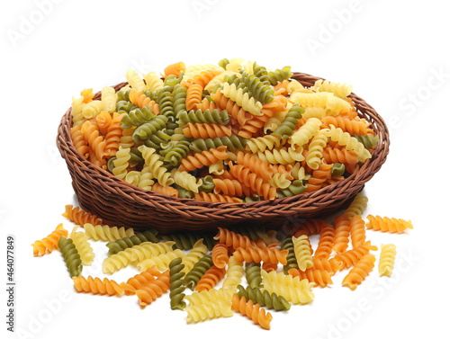 Colorful Italian spiral shaped pasta in wooden wicker basket macaroni fusilli tricolore isolated on white