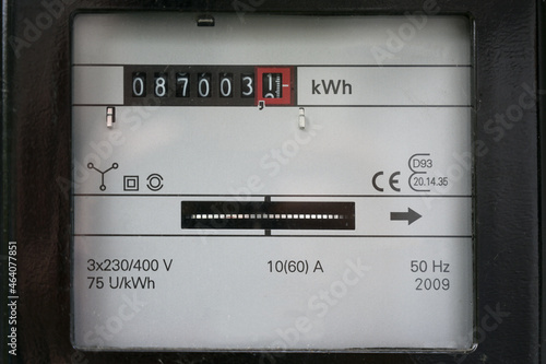 Electricity meter counting kilowatt hours consumed at home, concept of saving money on power consumption during rising energy prices photo