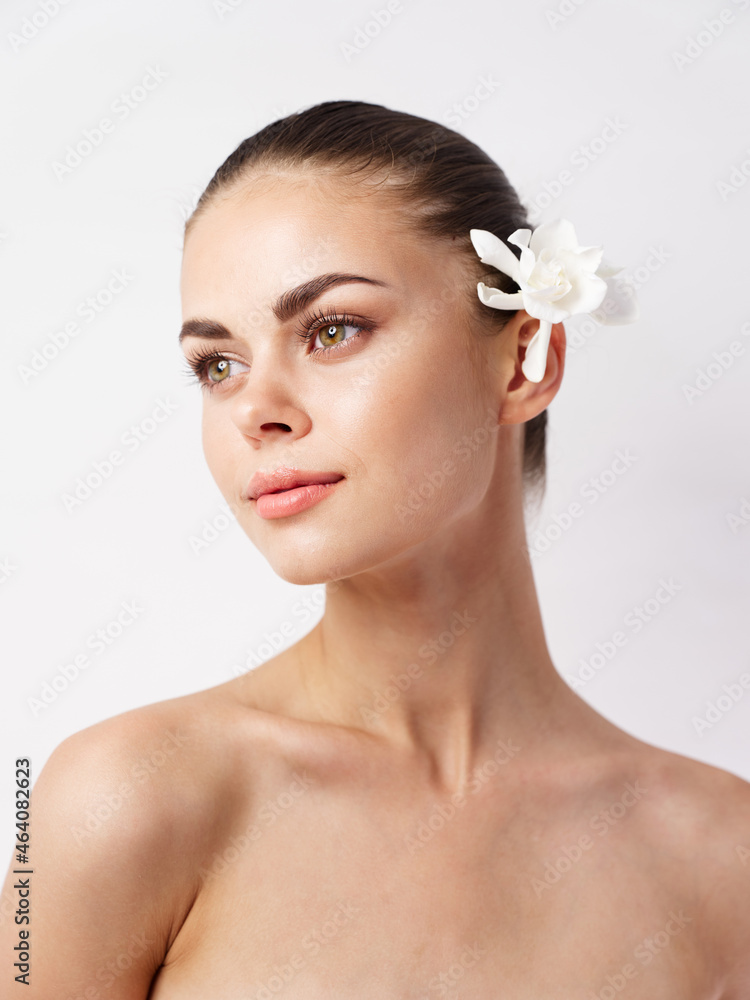 Fototapeta premium beautiful woman with bare shoulders bright makeup white flower look to the side