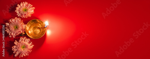 Happy Diwali. Diya oil lamp and flowers on red background. Traditional Hindu celebration. Religious holiday of light.