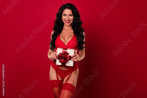 Portrait of attractive slim cheerful wavy-haired girl holding romantic giftbox 14 February isolated over bright red color background © deagreez