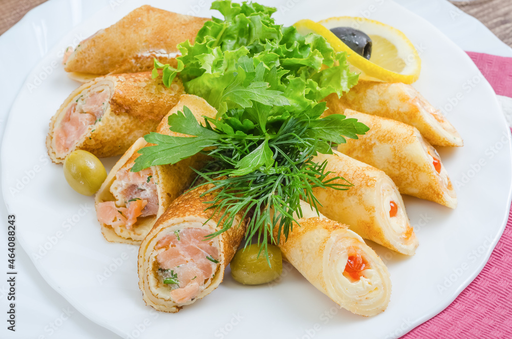 Crepes stuffed with fish, cheese and red caviar garnished with herbs on a white plate close-up Crepes stuffed with fish, cheese and red caviar garnished with herbs on a white plate close-up