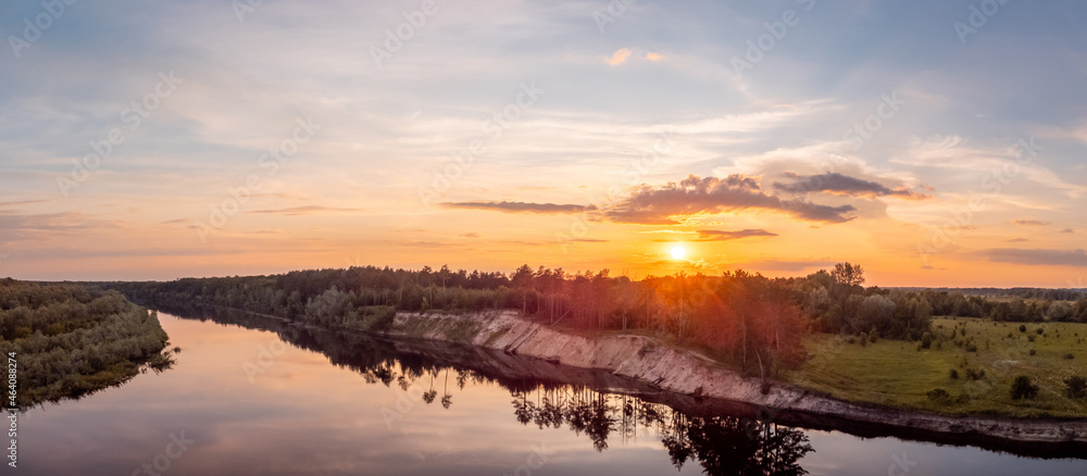 Wide panorama of river Desna with a high bank and a setting sun on the background. Drone landscape of a rural nature in the evening