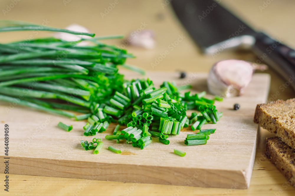 chropped green onions on a wooden board and garlic, bread,pepper and knife chropped green onions on a wooden board and garlic, bread,pepper and knife