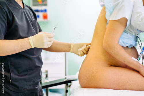 Close up of unrecognizable male doctor injecting Epidural Anesthesia for pregnancy Labor during childbirth for woman pathient in hospital. Prepare for surgery. Medical background
