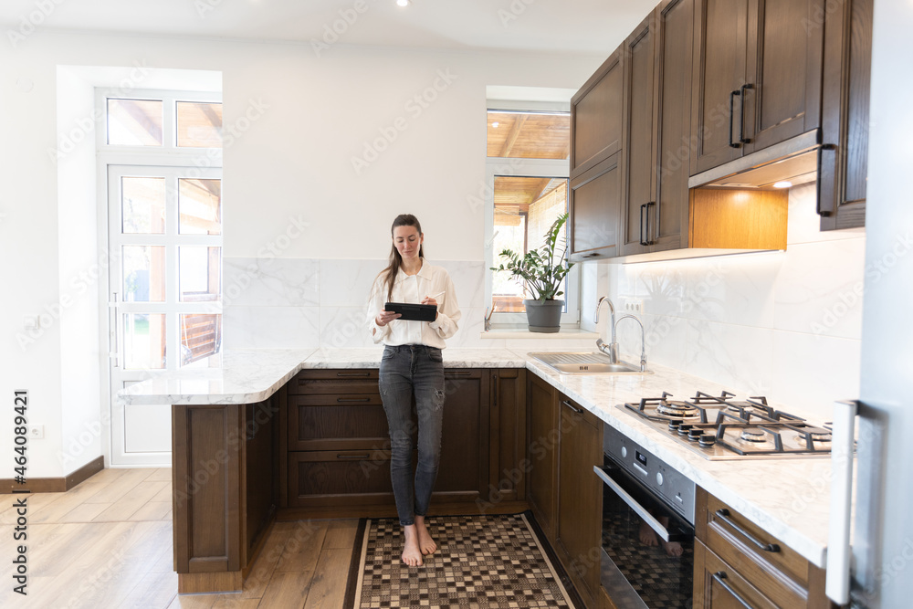 Woman working in her kitchen from home in a modern scandinavian kitchen Woman working in her kitchen from home in a modern scandinavian kitchen