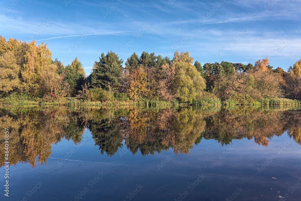 Autumn landscape with trees reflecting in the calm water of a forest lake in sunny morning Autumn landscape with trees reflecting in the calm water of a forest lake in sunny morning