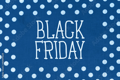 Black Friday sign on polka dot blue fabric with printed white circles. Shopping concept