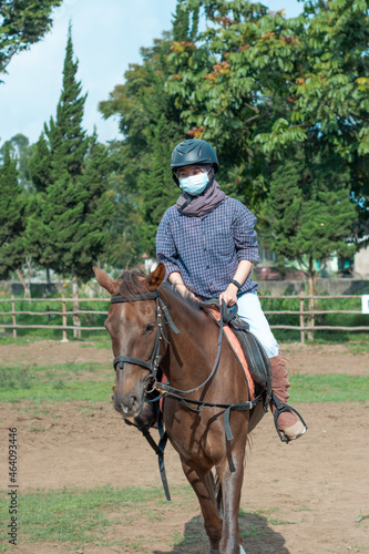 Women with mask and hijab learns to ride a horse. girls riding horses at the ranch. equestrian sport during the pandemic