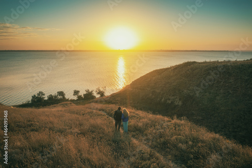 Seascape in an autumn evening. Young couple stands on a hill in the evening and looks at a beautiful sunset