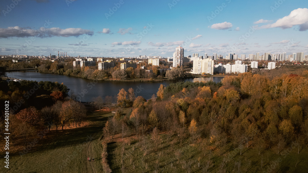 Flight over the autumn park. On the horizon there is a city houses.  Trees with yellow autumn leaves are visible.  Aerial photography.