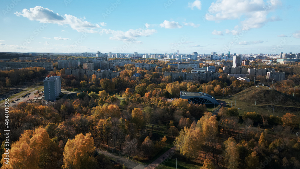 Flight over the autumn park. On the horizon there is a city houses.  Trees with yellow autumn leaves are visible.  Aerial photography.