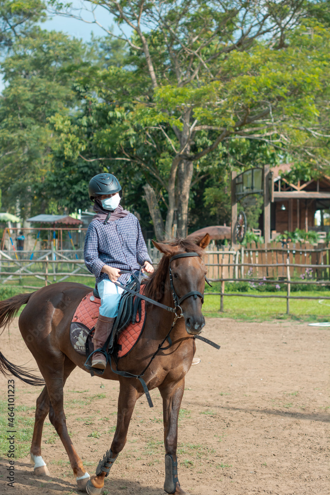 Women with mask and hijab learns to ride a horse. girls riding horses at the ranch. equestrian sport during the pandemic Women with mask and hijab learns to ride a horse. girls riding horses at the ranch. equestrian sport during the pandemic