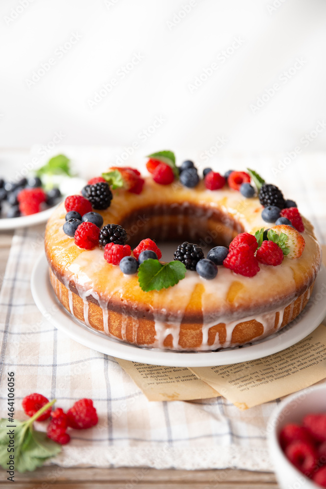 Ciambella decorata con frutti di bosco e menta e con una glassa di limone Ciambella decorata con frutti di bosco e menta e con una glassa di limone