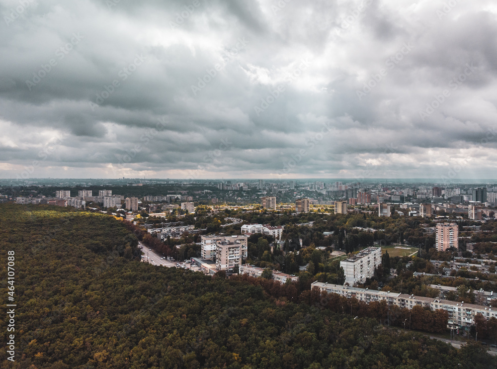 Cityscape aerial with dramatic clouds. Kharkiv city Pavlovo Pole district, view on Derevianka street with residential buildings from autumn dark forest