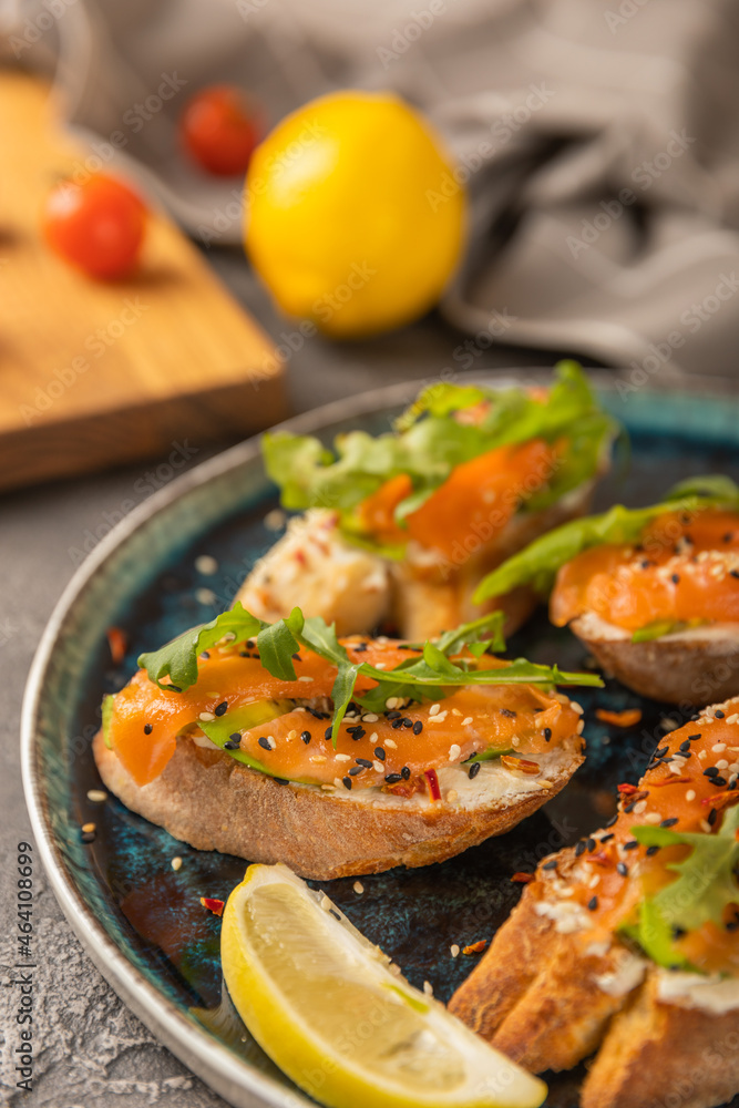 delicious bruschetta with salmon avocado and arugula on a large blue plate.