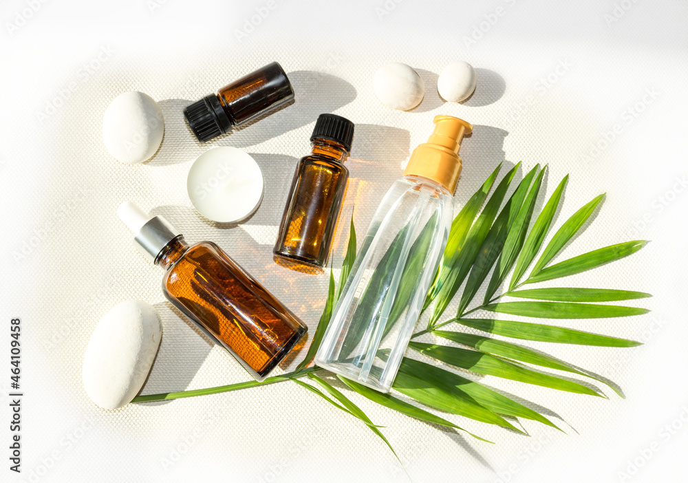 bottles and dispensers with natural cosmetics or oils on white background and tropical leaf bottles and dispensers with natural cosmetics or oils on white background and tropical leaf