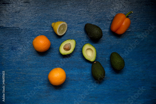 Fruits and vegetables on the blue wooden background. Oranges, avocado, pepper, lemon.