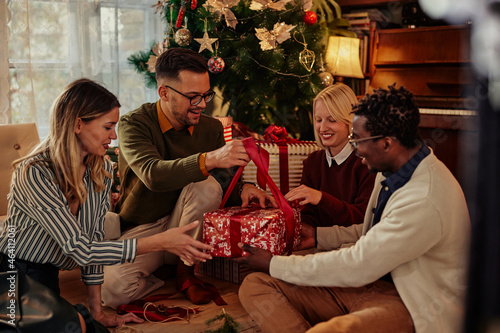Slika na platnu Cheerful friends opening Christmas present