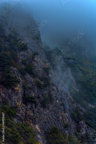 Stony slopes of mountain in dense fog.