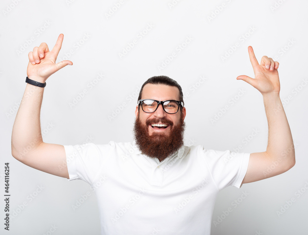 Happy bearded man is pointing up with both arms. Happy bearded man is pointing up with both arms.