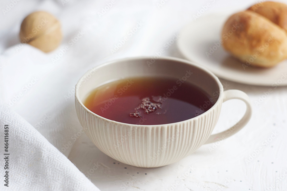 Black tea in a mug on the table. Nearby are croissants, a towel and nuts. Breakfast