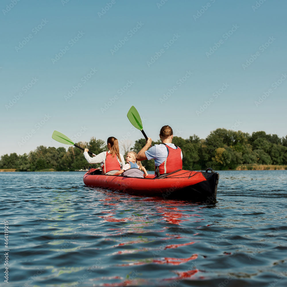 Young caucasian family floats on kayak in lake