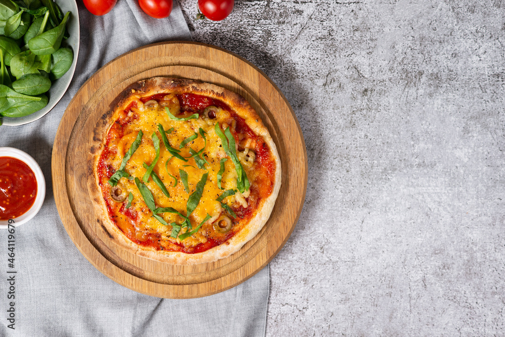 Homemade baked salami pizza on yeast-free dough on round wooden board. Served with ingredients: spinach, red sauce, tomatoes. Simple recipe for cooking. Light gray concrete background, copy space Homemade baked salami pizza on yeast-free dough on round wooden board. Served with ingredients: spinach, red sauce, tomatoes. Simple recipe for cooking. Light gray concrete background, copy space