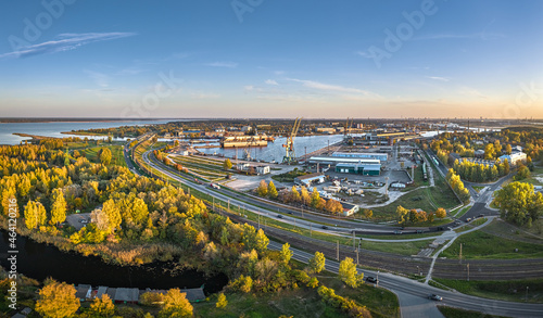 Aerial view of industrial district of Riga in autumn colors. Port of Riga with repair docks, golf course and highway.