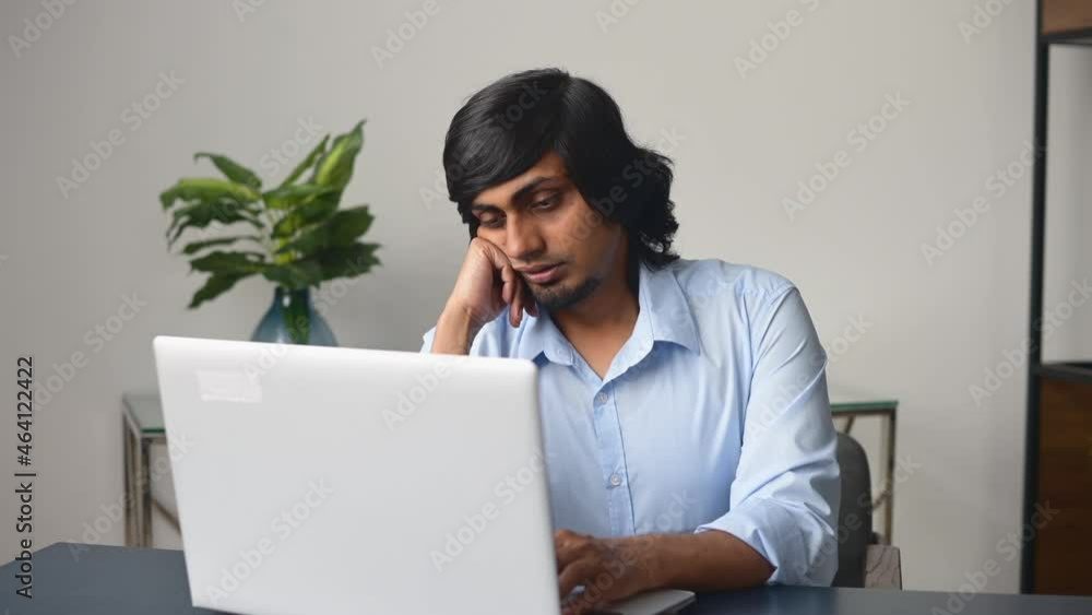 Tired and bored indian male office employee staring at the laptop screen, feels boring and melancholy. Bored eastern man in smart casual shirt sits at the desk Tired and bored indian male office employee staring at the laptop screen, feels boring and melancholy. Bored eastern man in smart casual shirt sits at the desk
