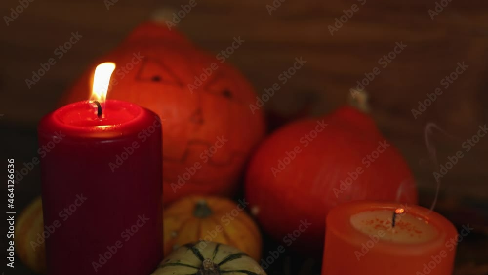 celebration halloween party holiday decoration: small pumpkins with drawing creepy scary face and two burning and going out red orange candles on wooden dark background. concept of finished over mood celebration halloween party holiday decoration: small pumpkins with drawing creepy scary face and two burning and going out red orange candles on wooden dark background. concept of finished over mood