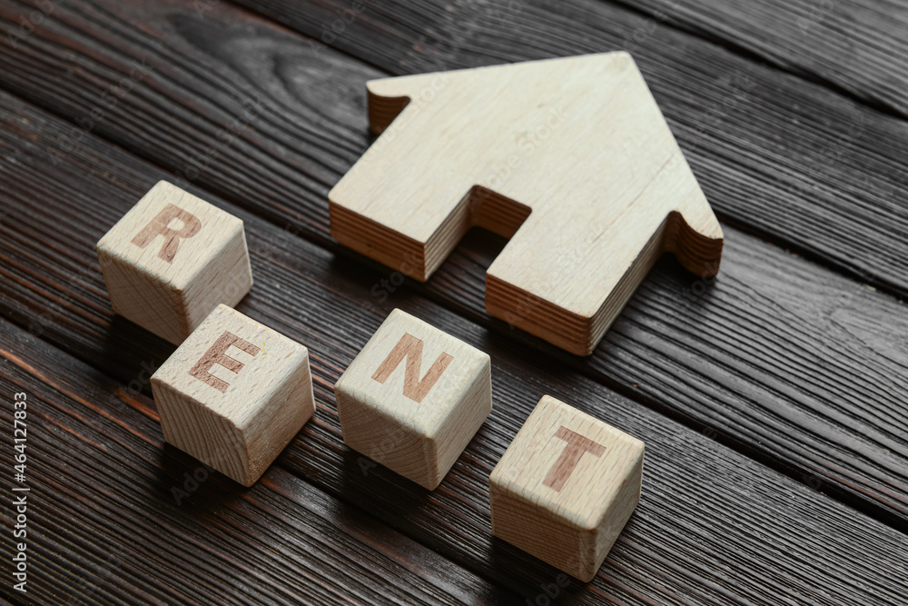 House with word RENT on dark wooden background, closeup House with word RENT on dark wooden background, closeup