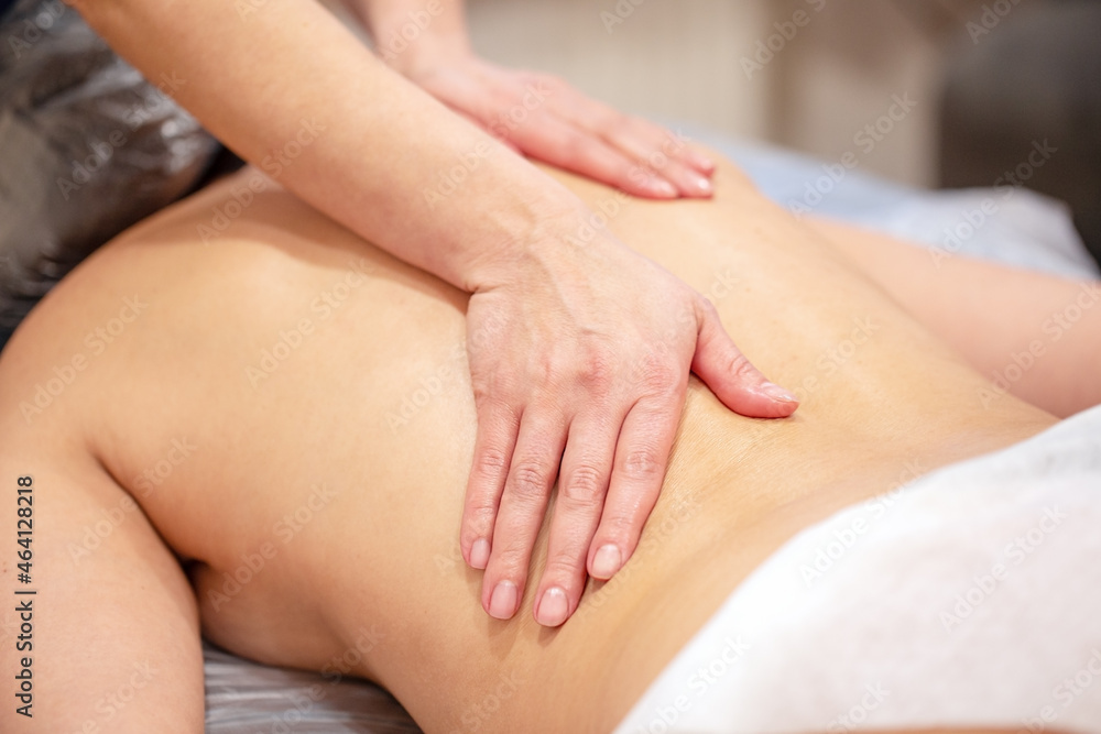 Hands of the masseur on back of young woman