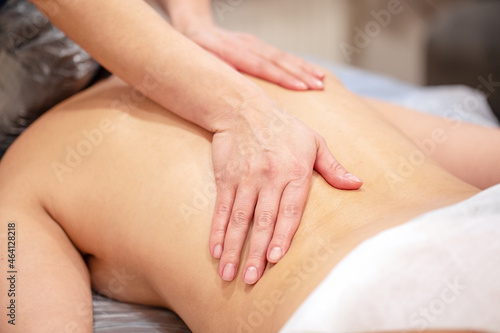 Hands of the masseur on back of young woman