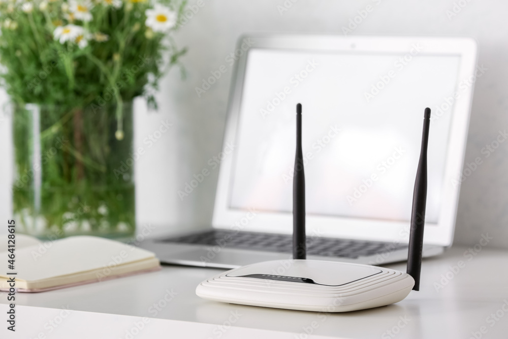 Modern wi-fi router on table near white wall Modern wi-fi router on table near white wall