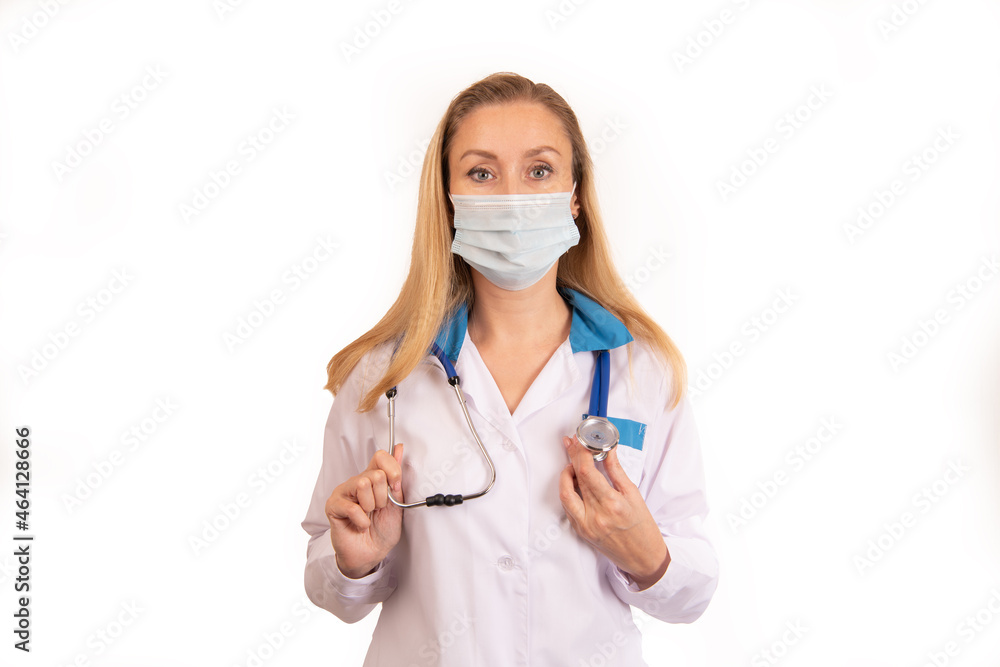 A young doctor girl on a white background in a white coat with a stethoscope around her neck and with her hair down in a mask holding a stethoscope A young doctor girl on a white background in a white coat with a stethoscope around her neck and with her hair down in a mask holding a stethoscope