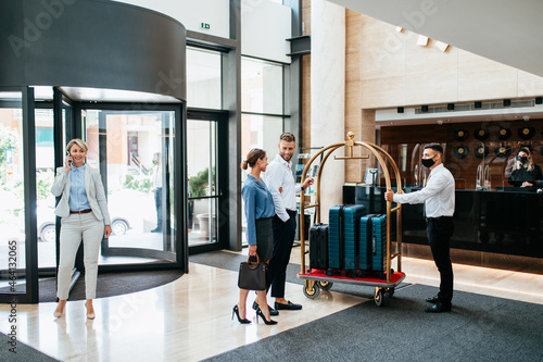 Fotografie Bellboy helping guests with their luggage cart in hotel hallway
