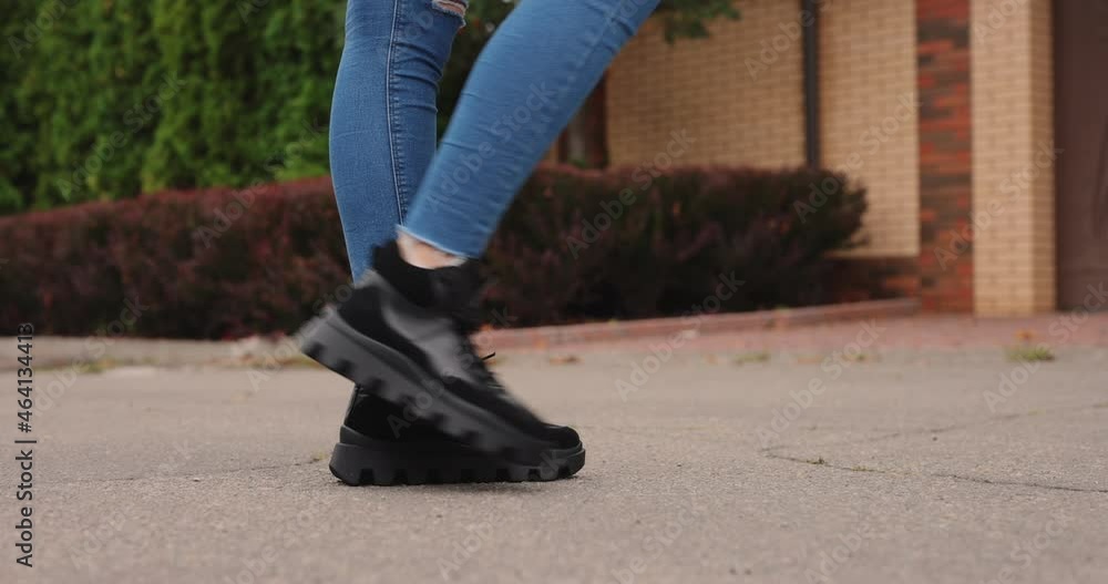 Women's black boots go on a pavement of the street Women's black boots go on a pavement of the street