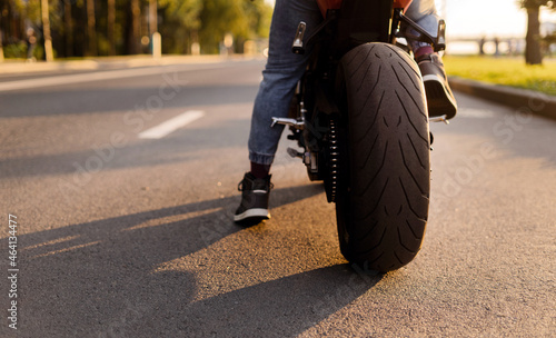 Summer season motorcycle on the road. The rear wheel protector rubber is new. A biker man in a protective bike suit.