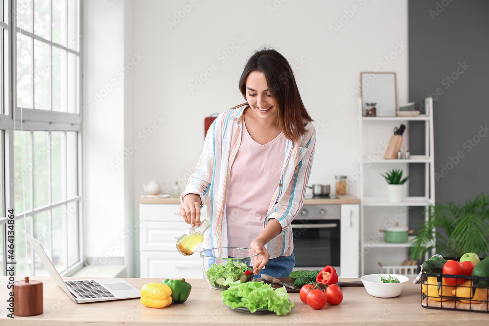 Young woman preparing fresh vegetable salad in kitchen