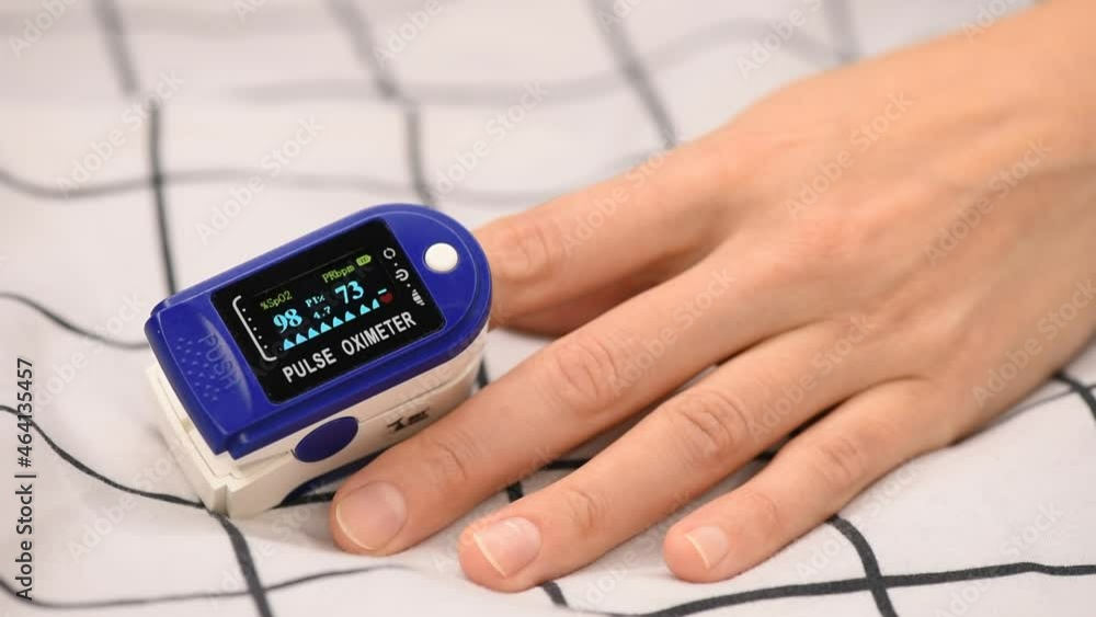 Close up of pulse oximeter on hand of young woman in bed. Close up of pulse oximeter on hand of young woman in bed.