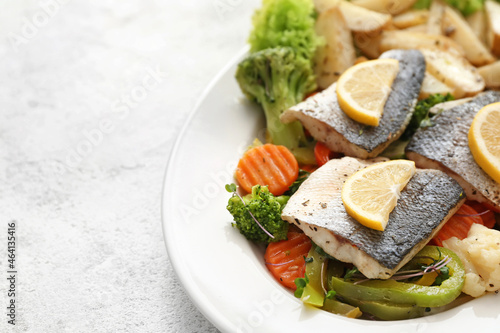 Photos Plate of tasty sea bass fish with vegetables on light background