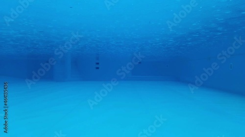 The view through a viewing port between floor, bottom and surface of swimming pool blue water during the rain, at the resort 