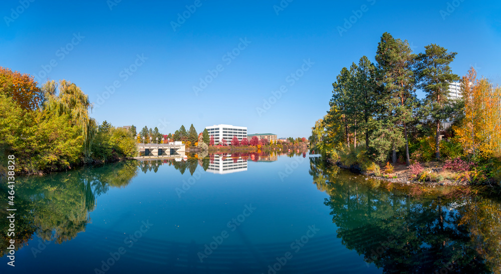 Panoramic view of the Upper Falls Reservoir and Dam at Riverfront Park in downtown Spokane, Washington, USA with leaves turning fall colors at autumn.